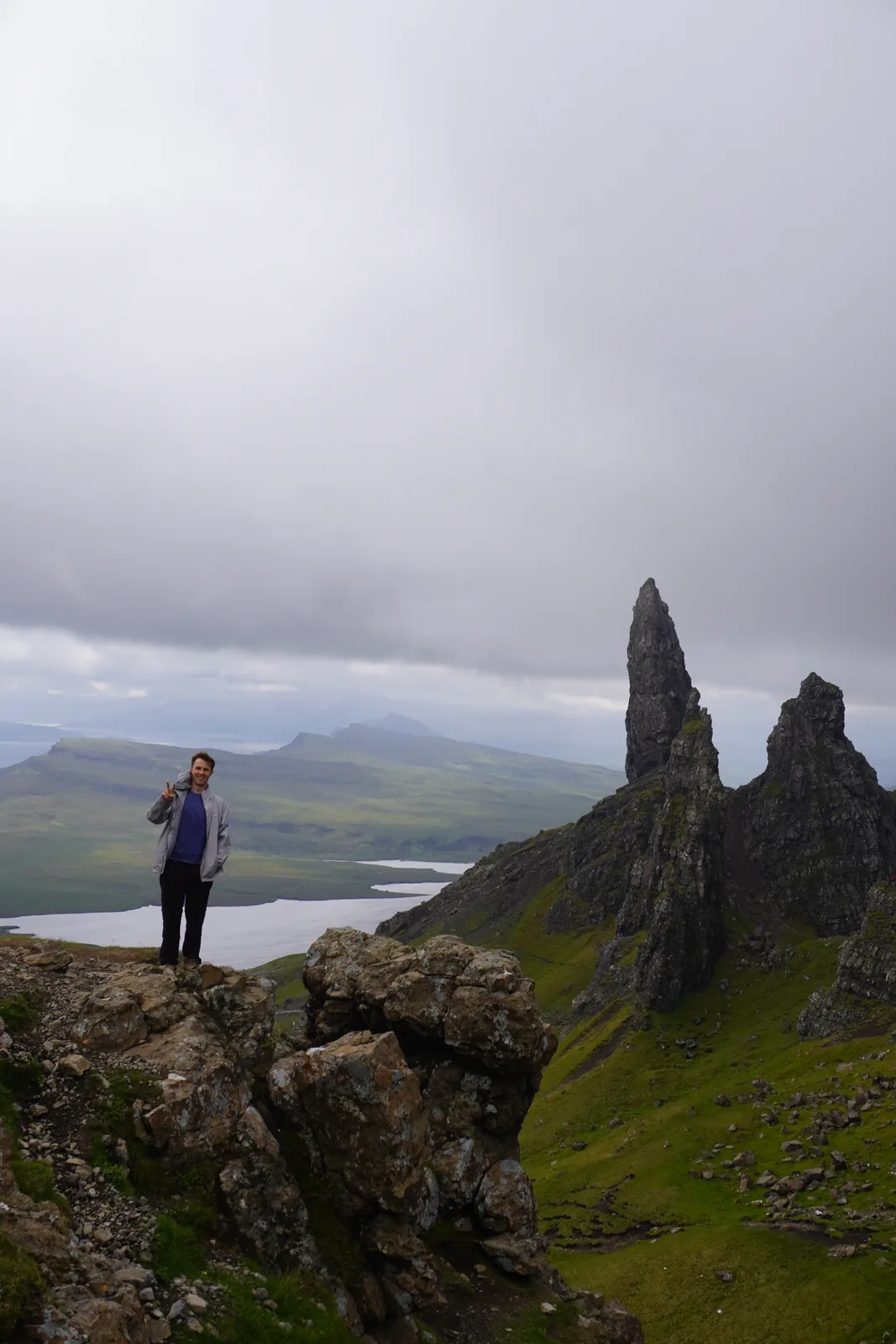 Sam giving a peace sign on a rocky summit above the clouds
